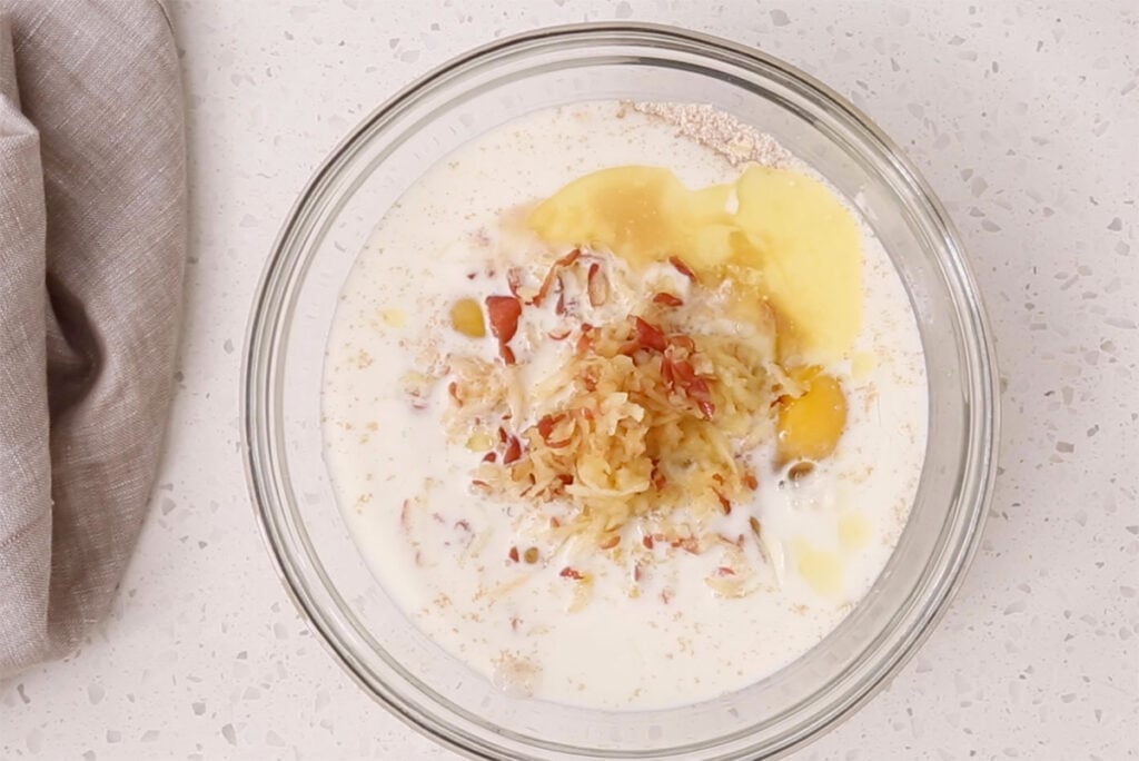 mixing apple pancake batter wet ingredients in bowl.