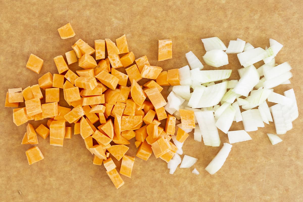 Diced sweet potato and onion on a cutting board.