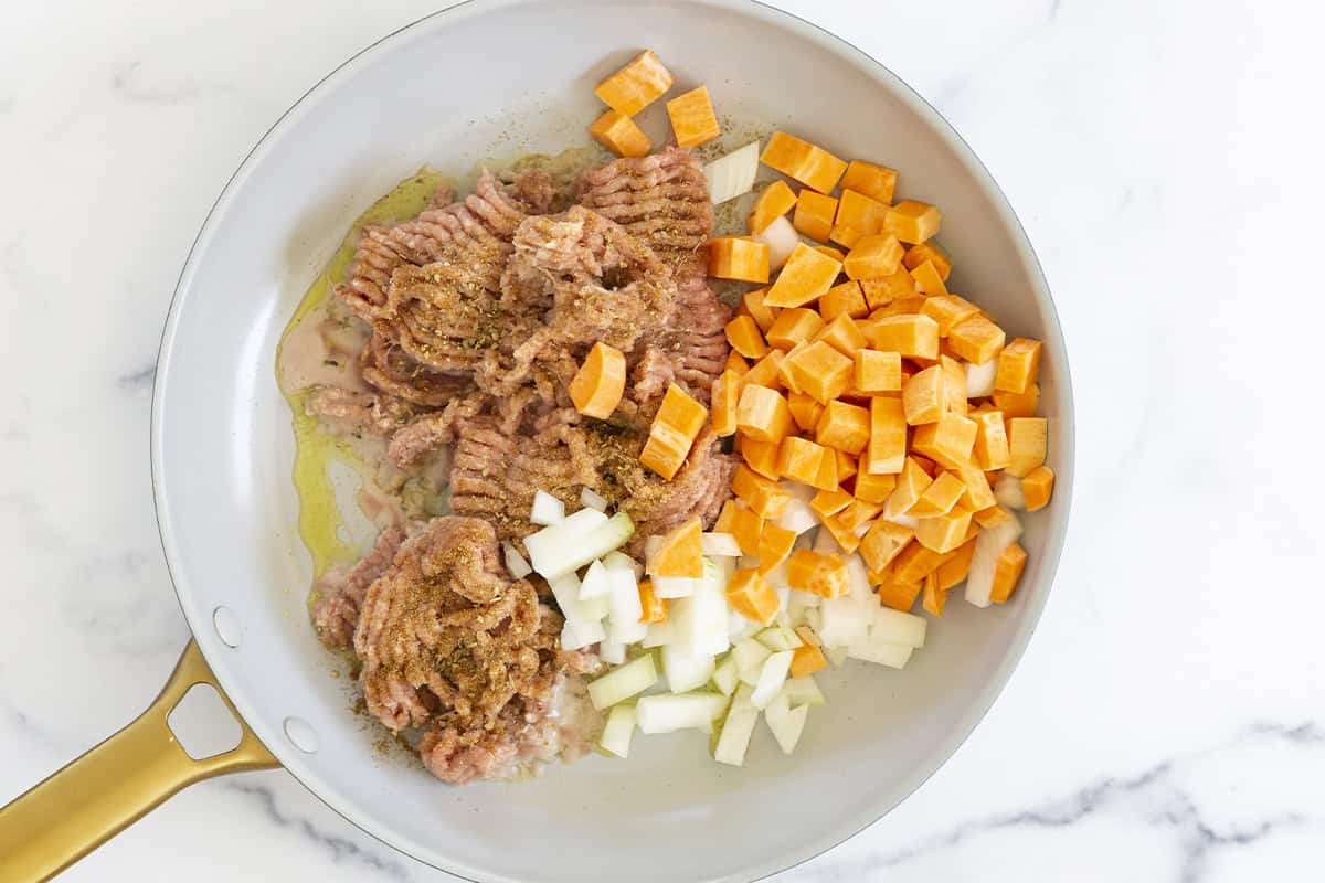 Ground turkey, sweet potato, and onion added to a skillet.