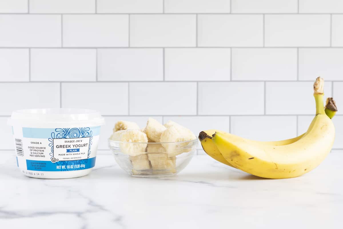 Banana smoothie with yogurt ingredients on countertop.