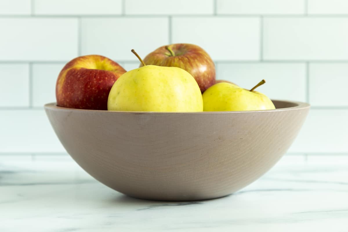 Apples in grey bowl on countertop.