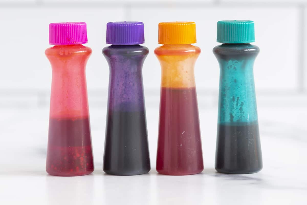 Food coloring in four bottles on countertop.
