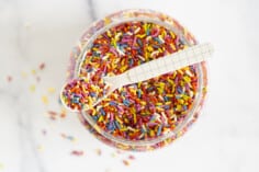 Sprinkles in jar with spoon from above.
