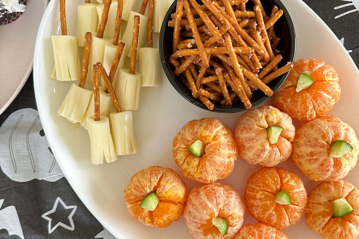 cheese brooms and clementine pumpkins on plates.