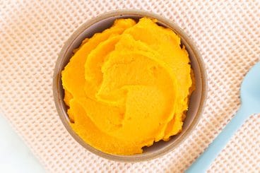 sweet potato puree in bowl with blue spoon.