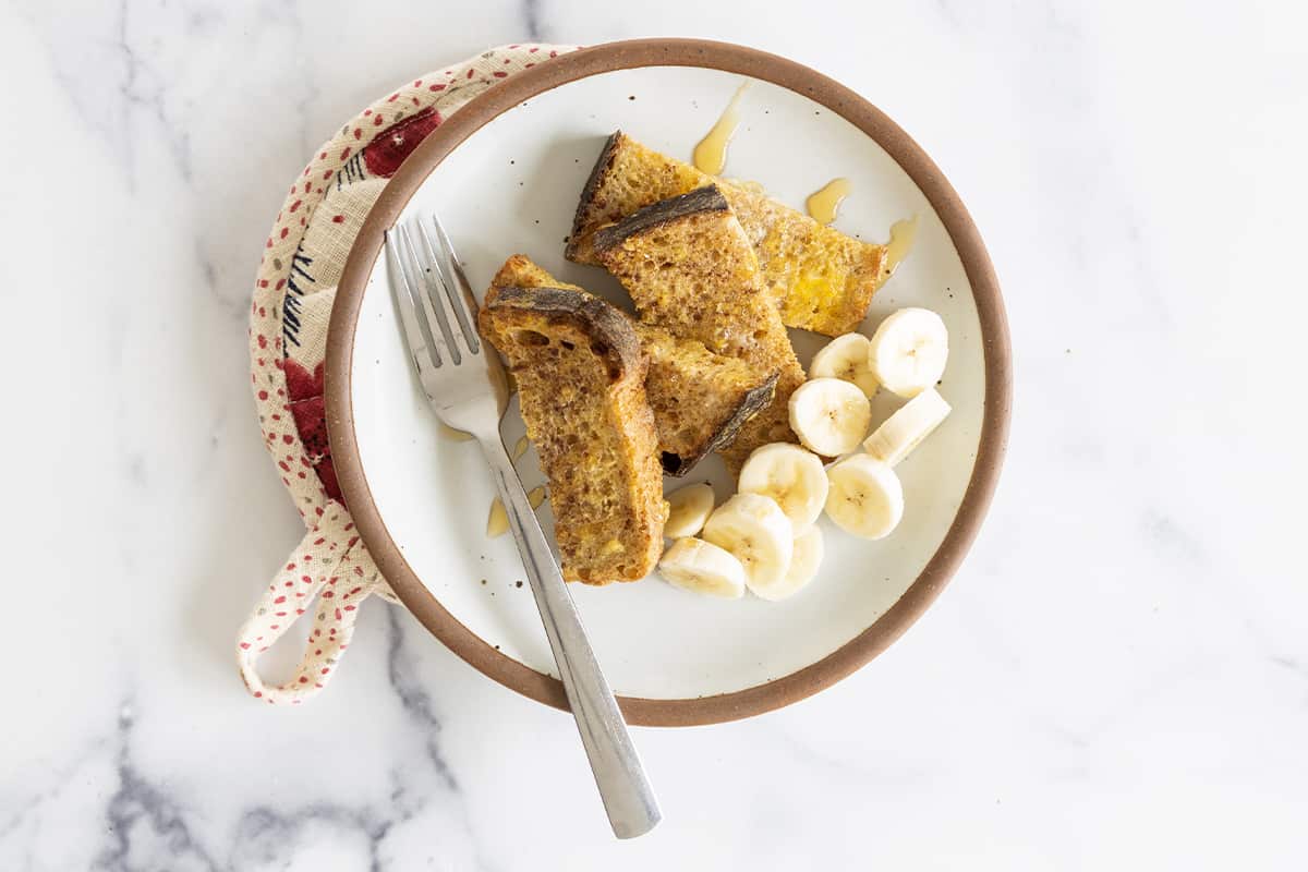 Air Fryer French Toast on plate with banana and syrup.