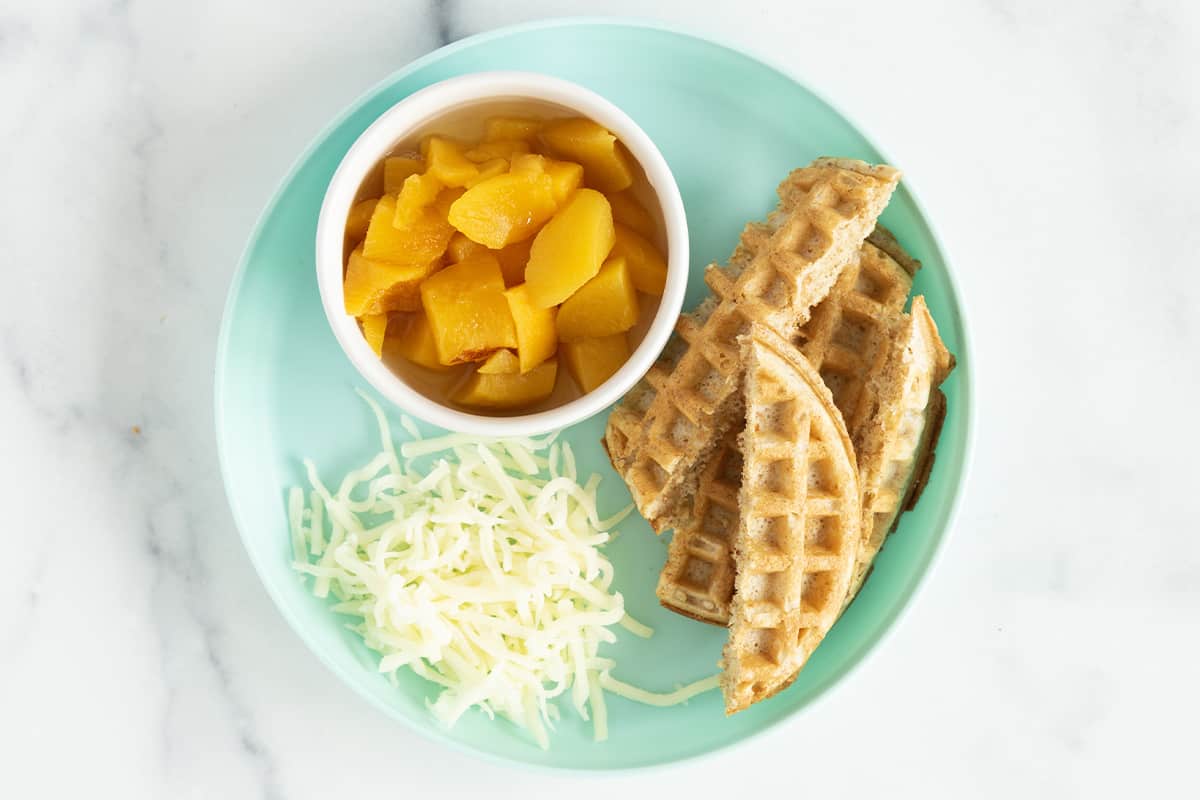 Waffles with cheese and mango on blue plate.