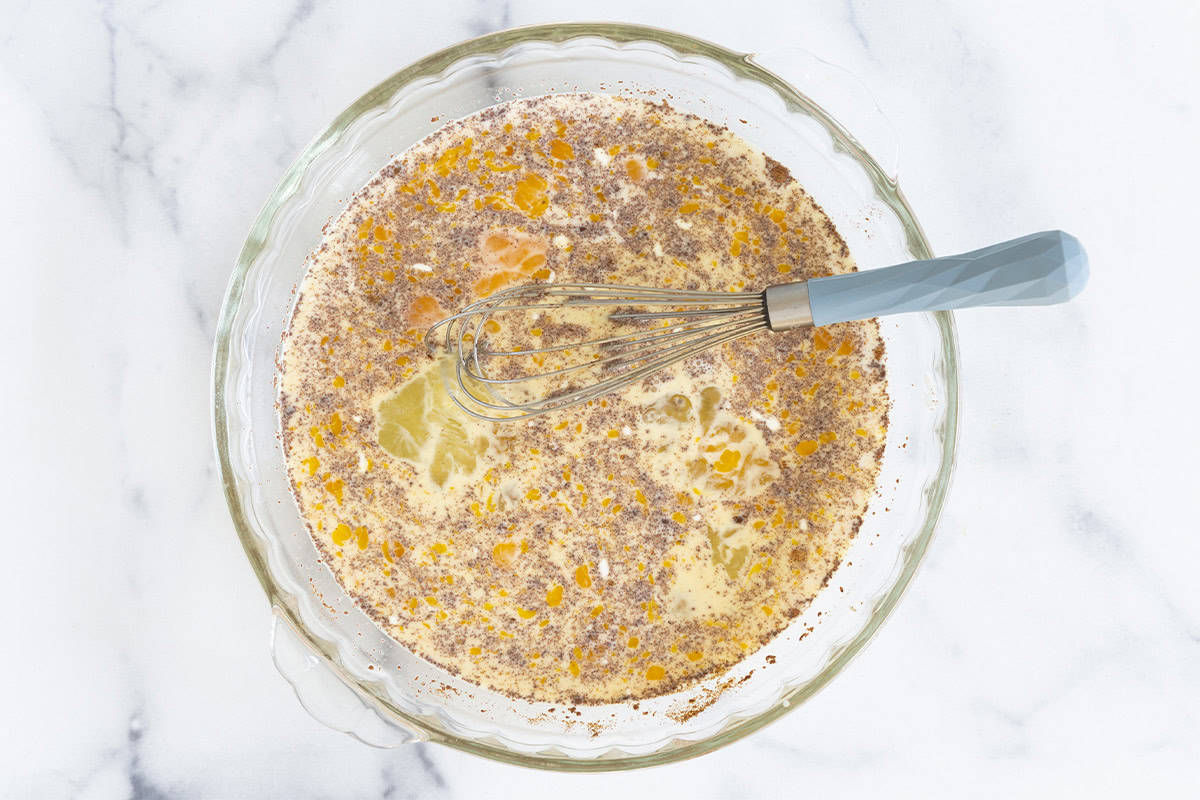 Mixture for oven baked french toast in glass bowl with whisk. 
