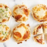 English muffin pizzas with different toppings, one cut up.