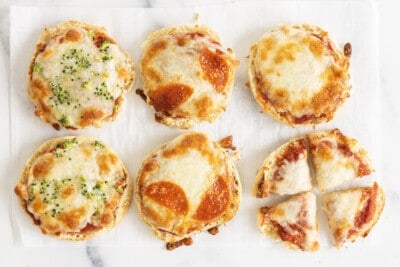 English muffin pizzas with different toppings, one cut up.