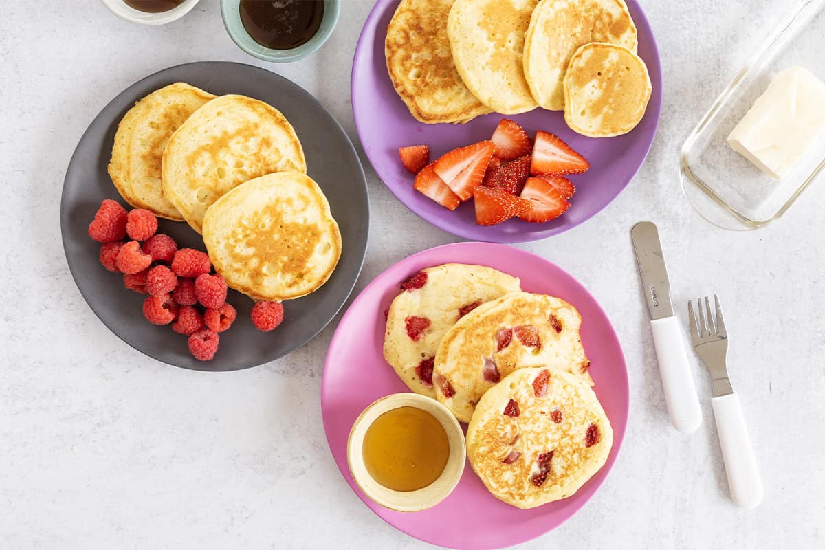 Greek yogurt pancakes on various plates with sides.