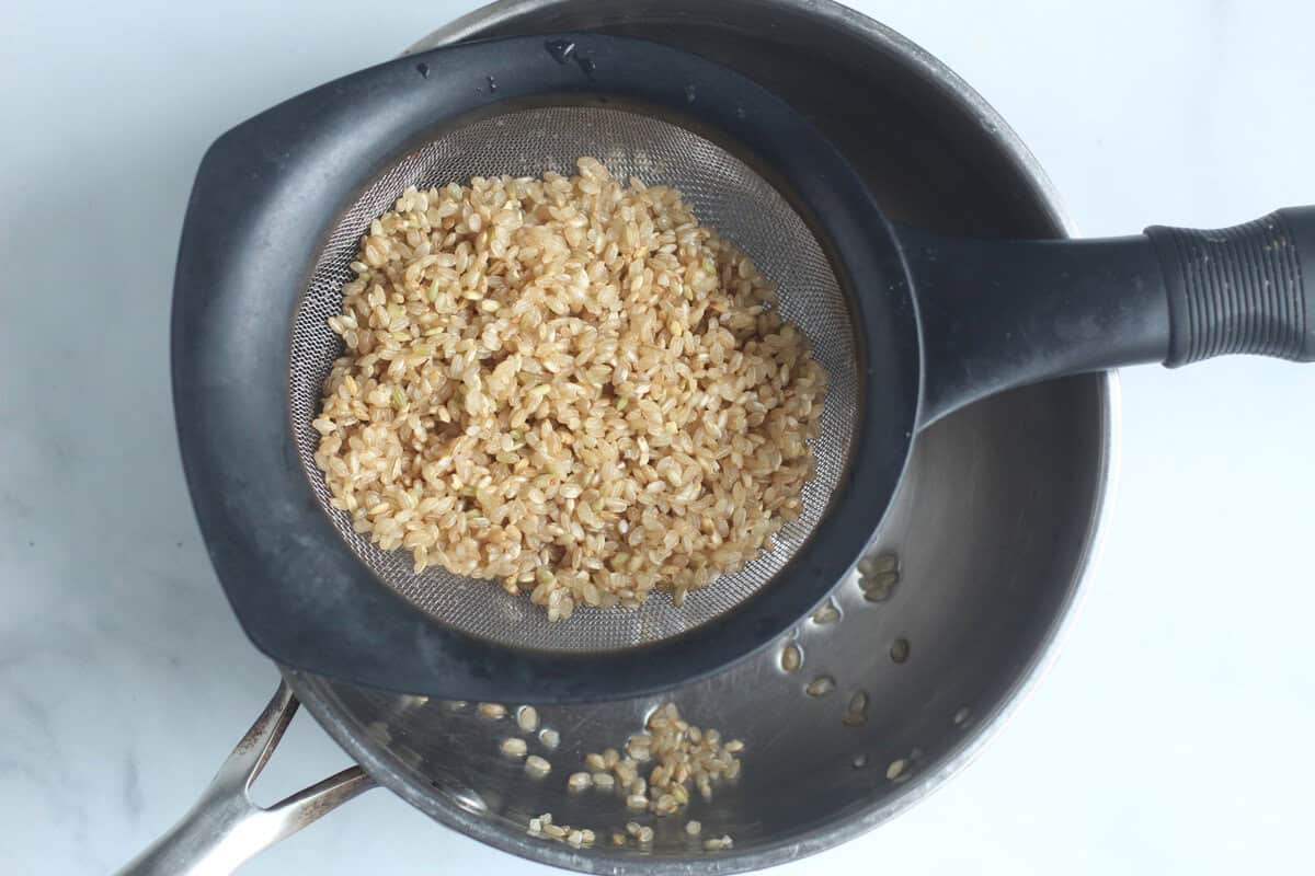 Making baby rice cereal, straining mixture over pot. 