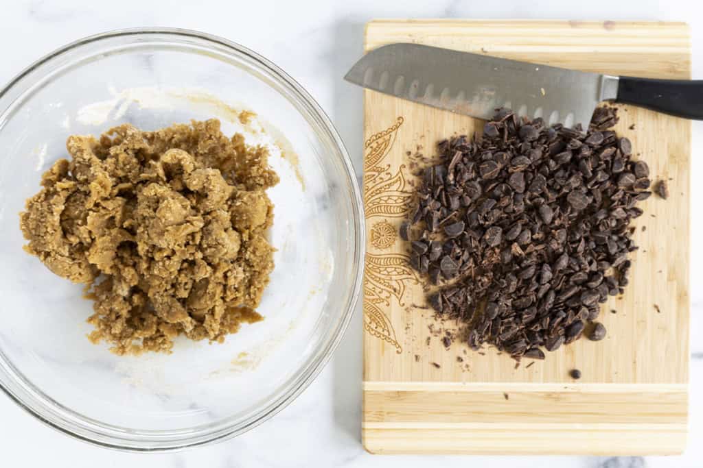 Chopping chocolate on cutting board for dairy free chocolate chip cookies.