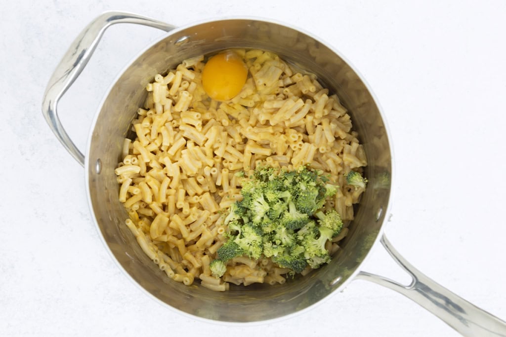 mac and cheese with egg and broccoli in pot for mac and cheese bites.