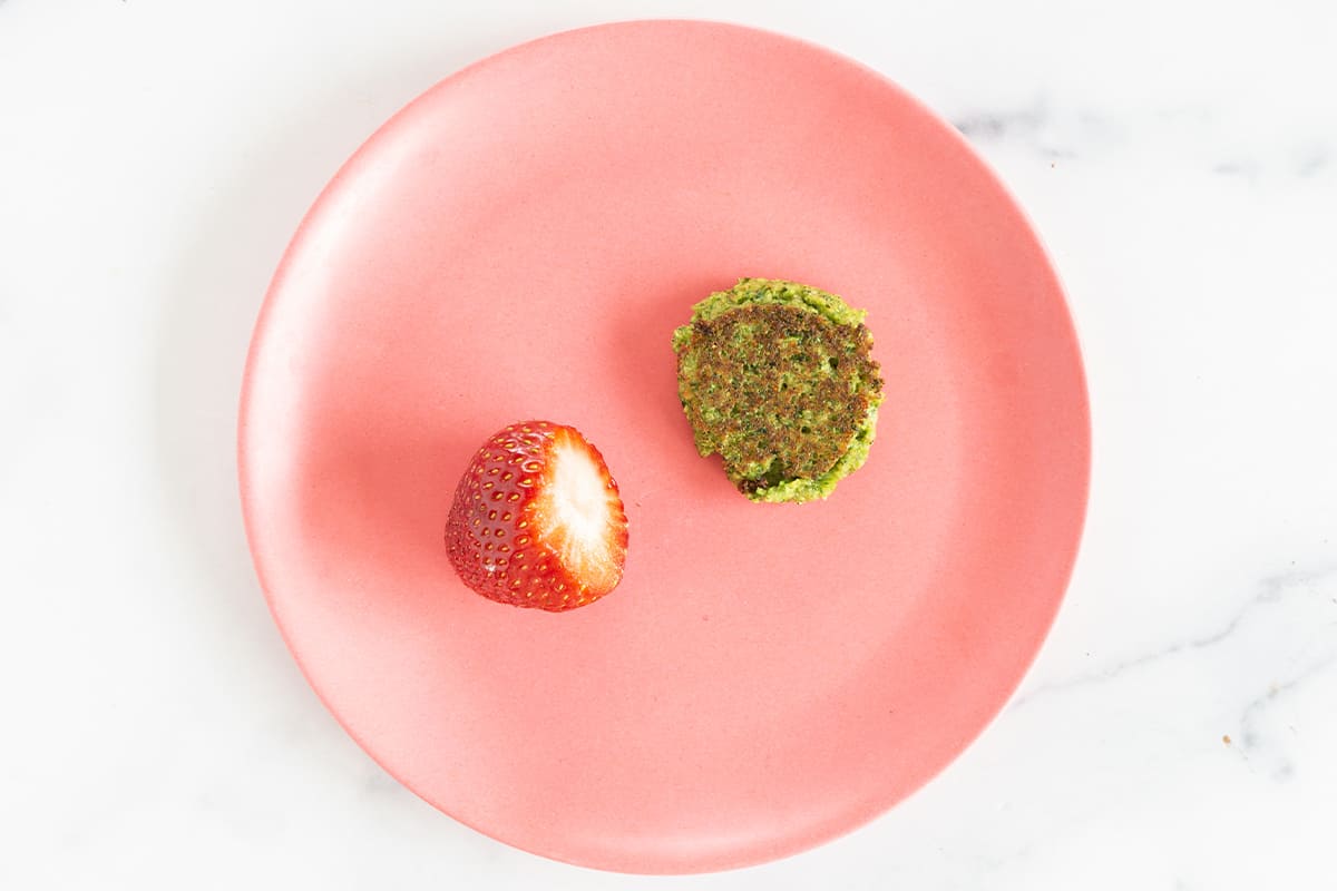 Broccoli fritter on pink plate with strawberry.