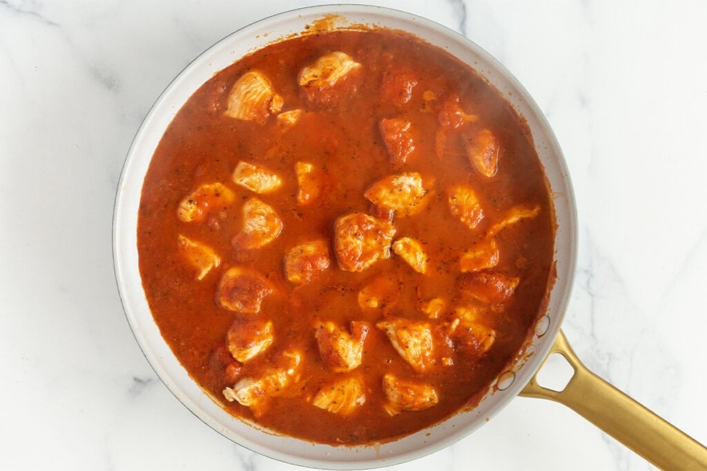 cooked chicken in marinara sauce in pan.