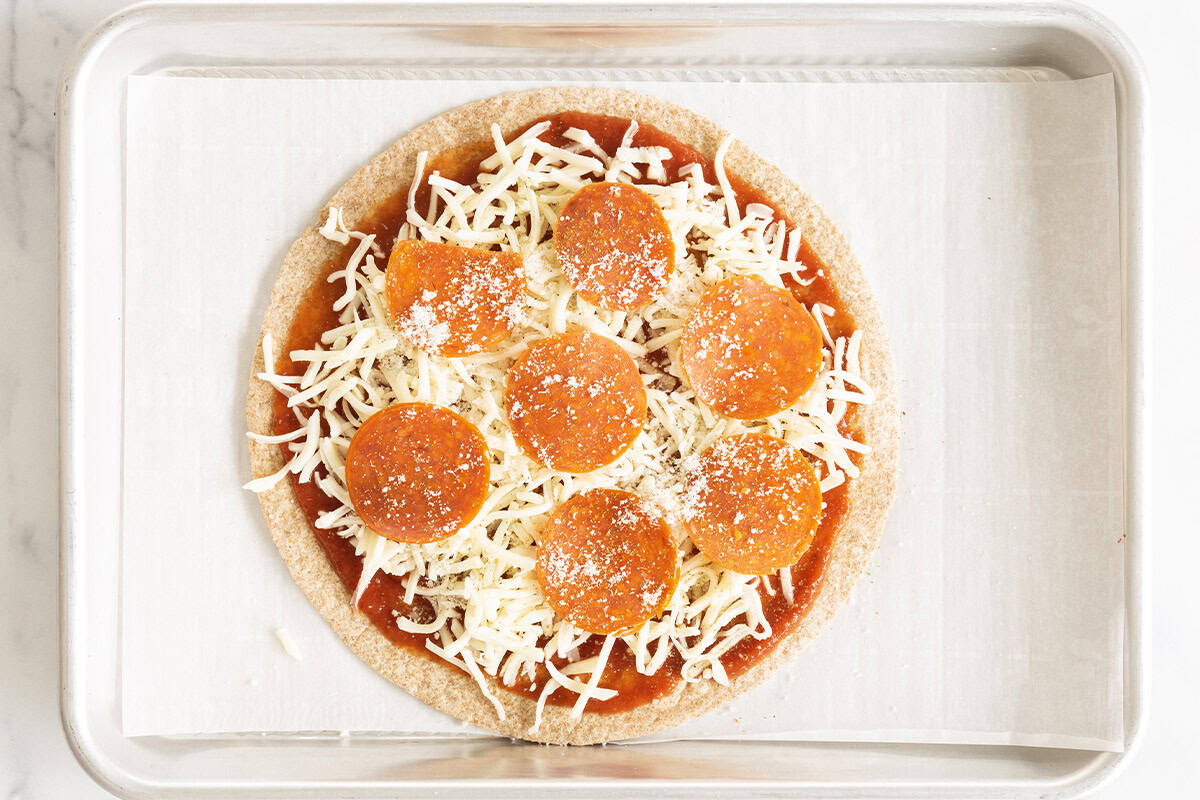 Tortilla pizza on baking sheet before baking. 