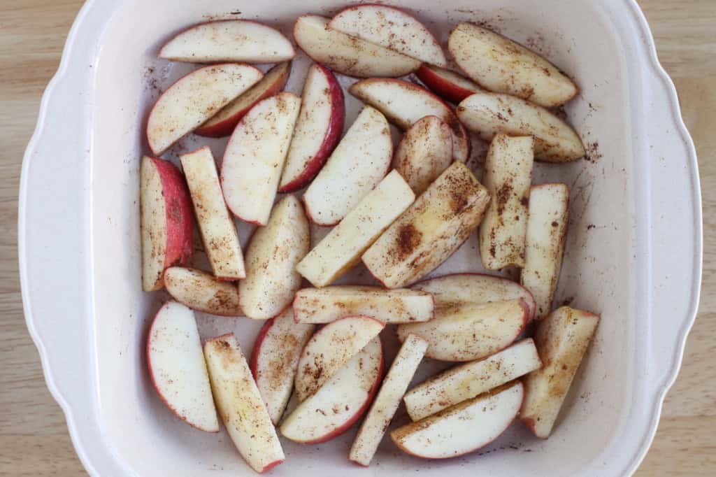 Apple slices in baking pan with cinnamon.