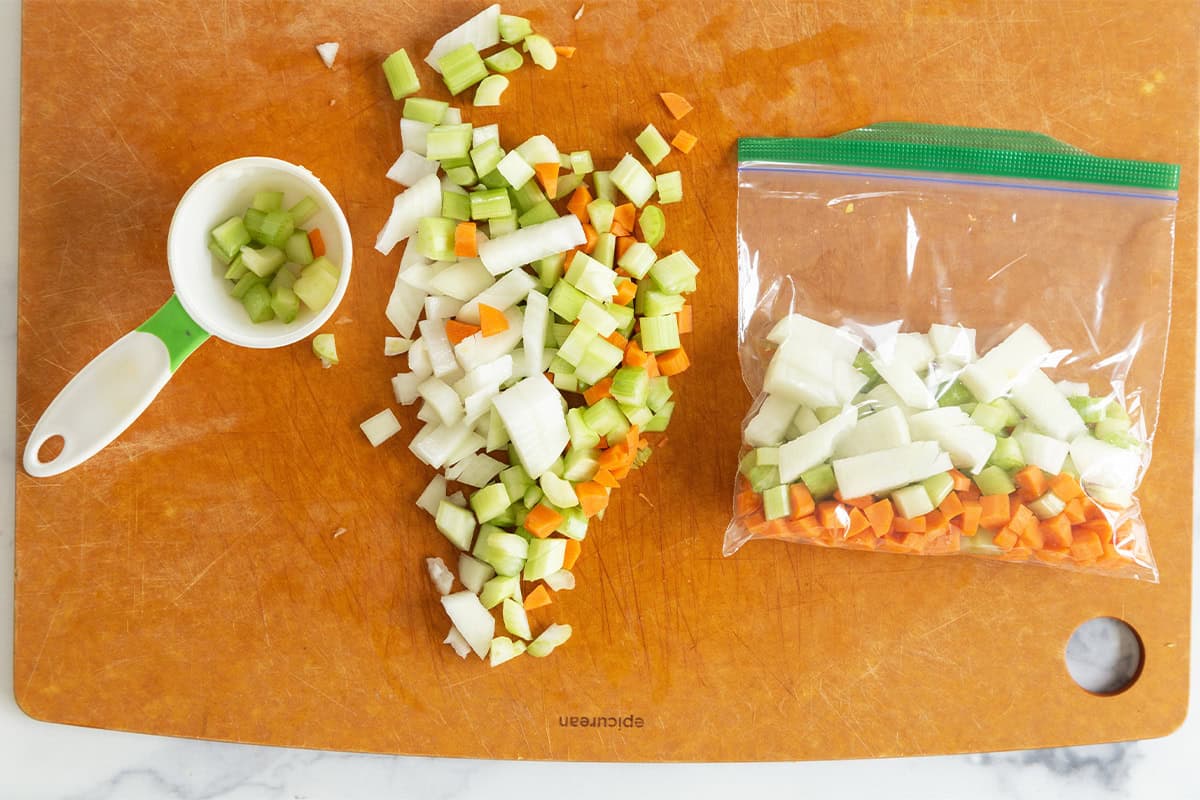 Adding chopped veggies to plastic bags to freeze mirepoix.
