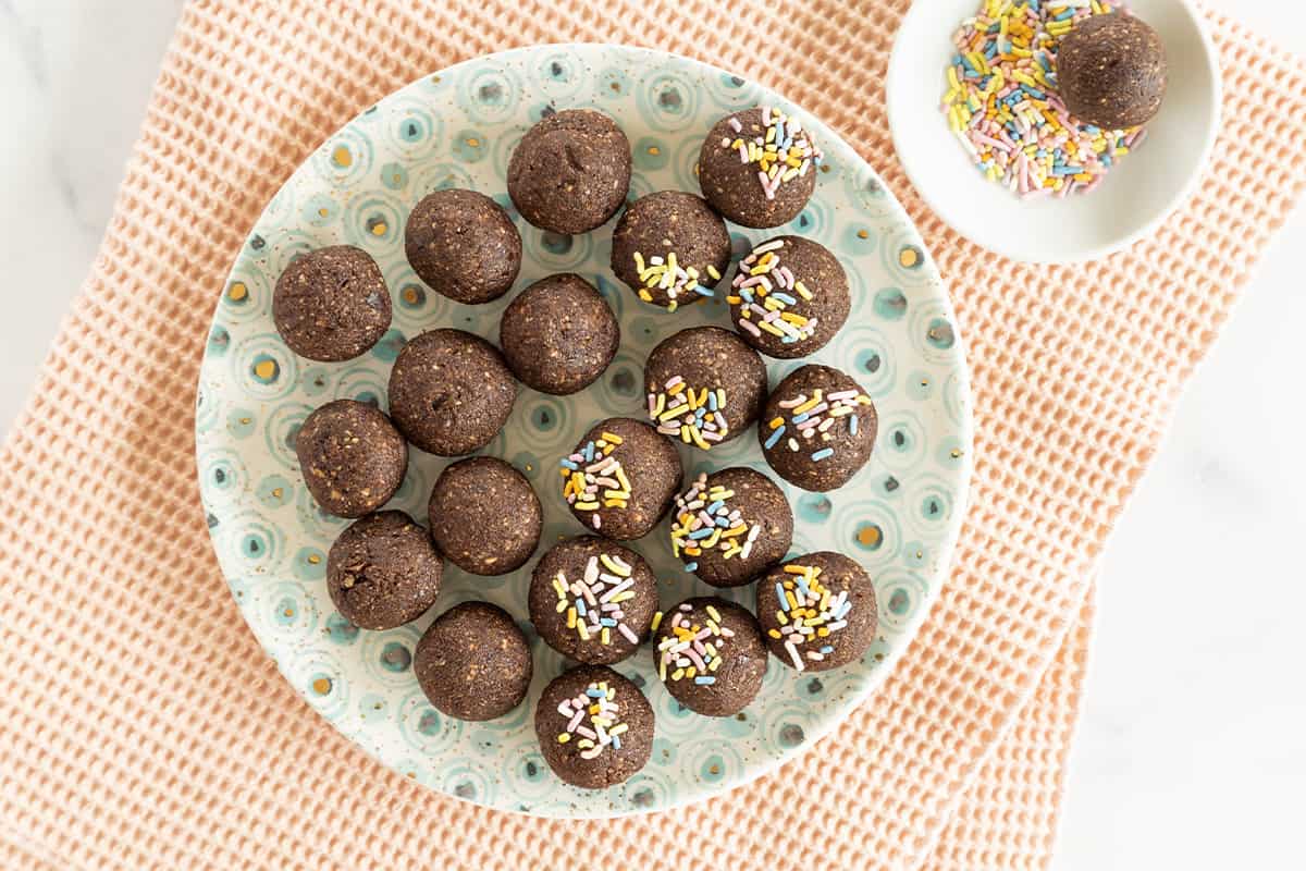 chocolate balls on plate with plate of sprinkles.