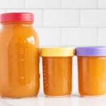 Vegetable broth in three glass jars with lids.