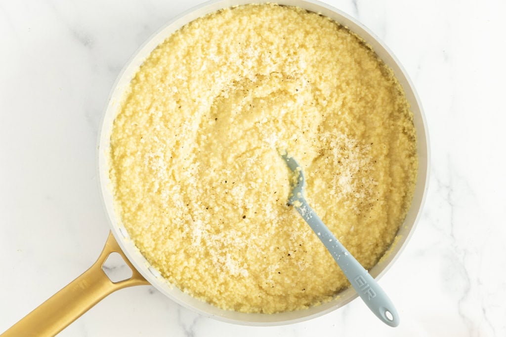 Pastina pasta being stirred in pot with blue spoon.