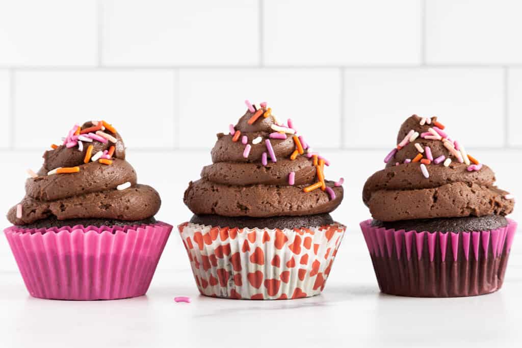 Three vegan chocolate cupcakes on counter.