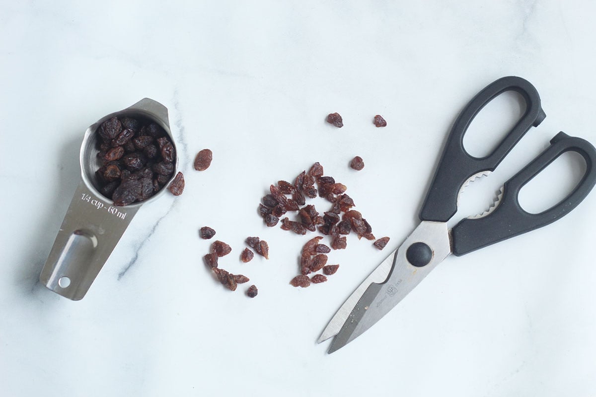 scissors and raisins on cutting board.
