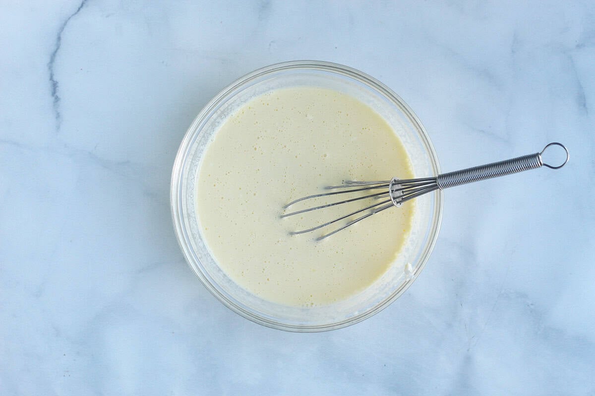 whisking wet ingredients in glass bowl for yogurt pancakes.