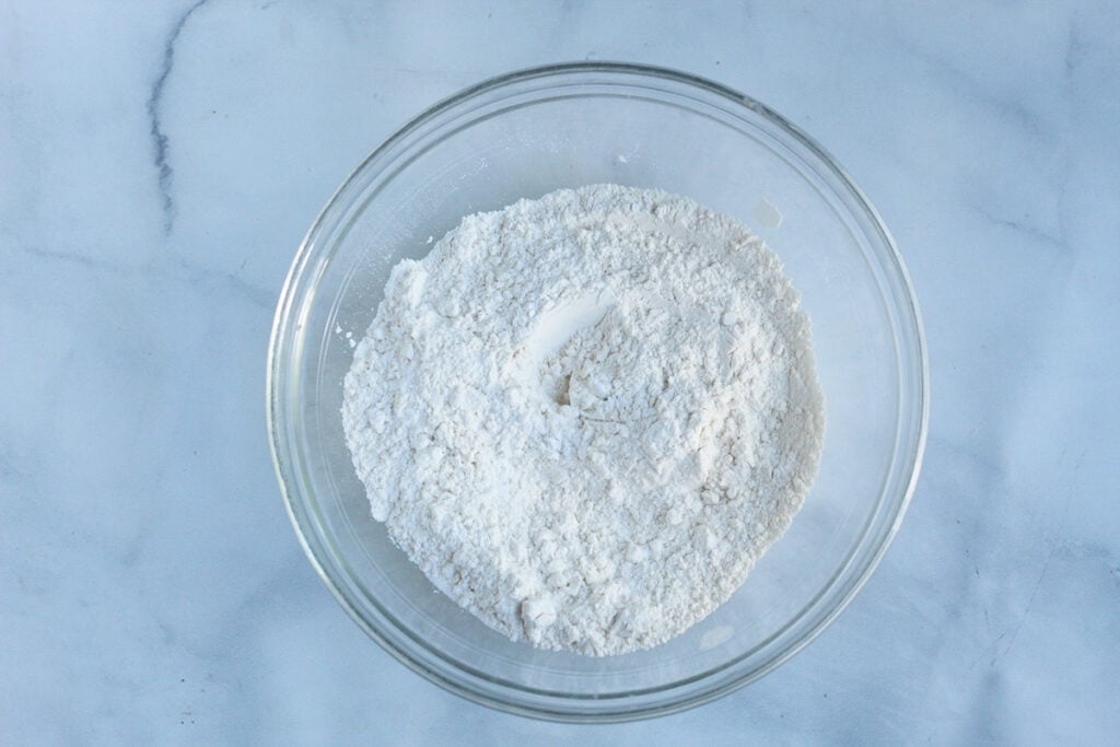 whisking dry ingredients for yogurt pancakes in glass bowl.