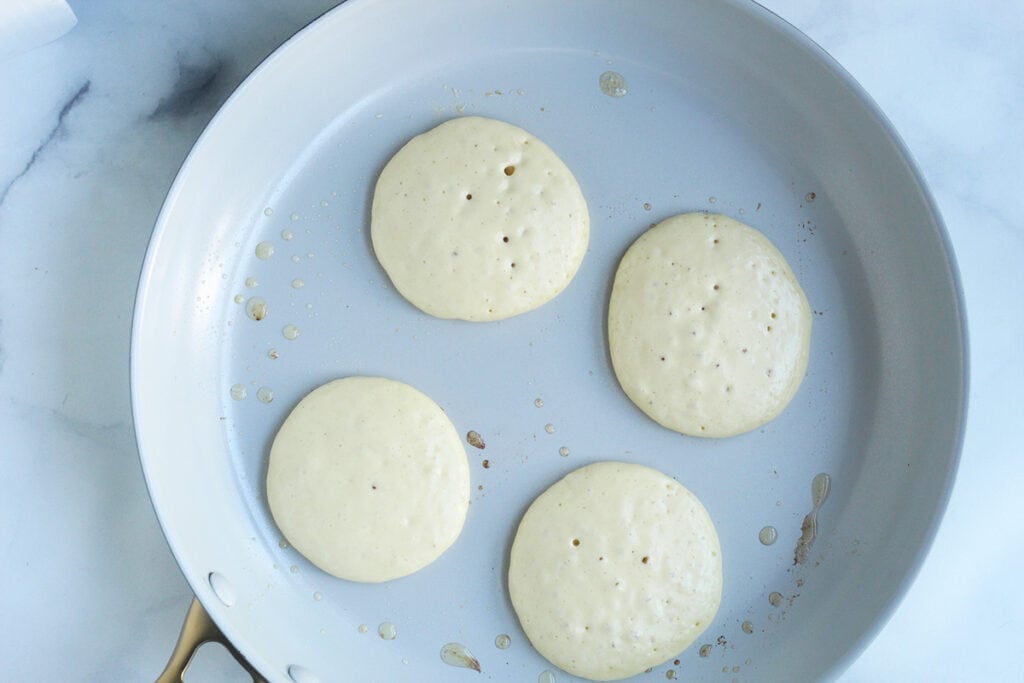 cooking yogurt pancakes in white pan on counter.