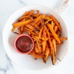 Air fryer roasted carrots on white plate with ketchup.
