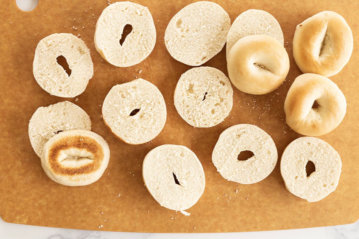 Bagels on cutting board cut in half for bagel pizza.
