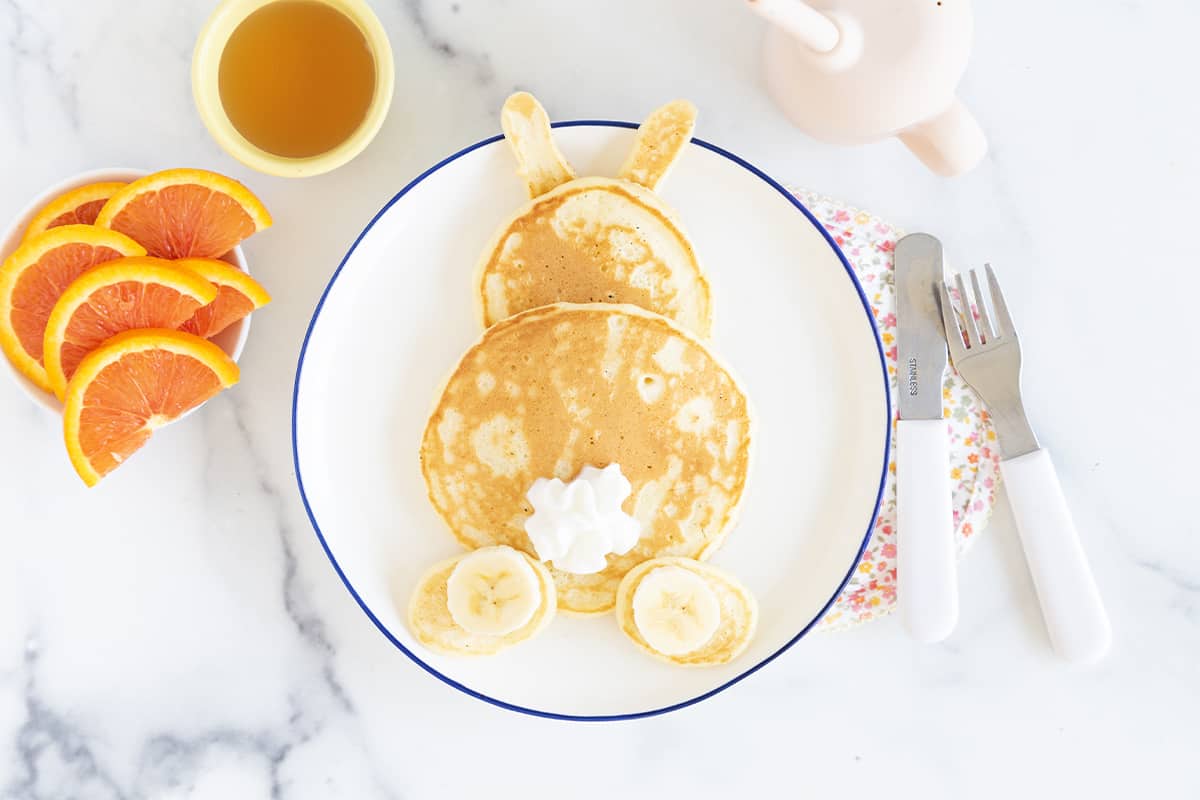Bunny pancakes on plate with orange slices as side.