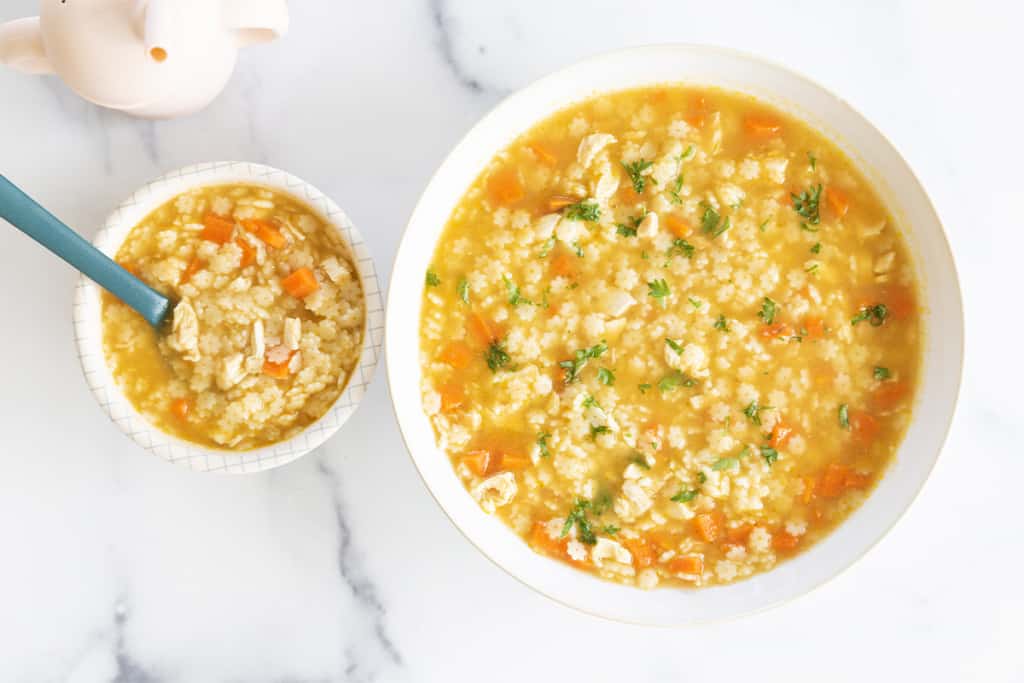 Chicken and stars soup in two white bowls.