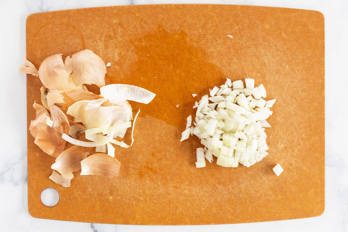 Onion being chopped on cutting board for orzo risotto.