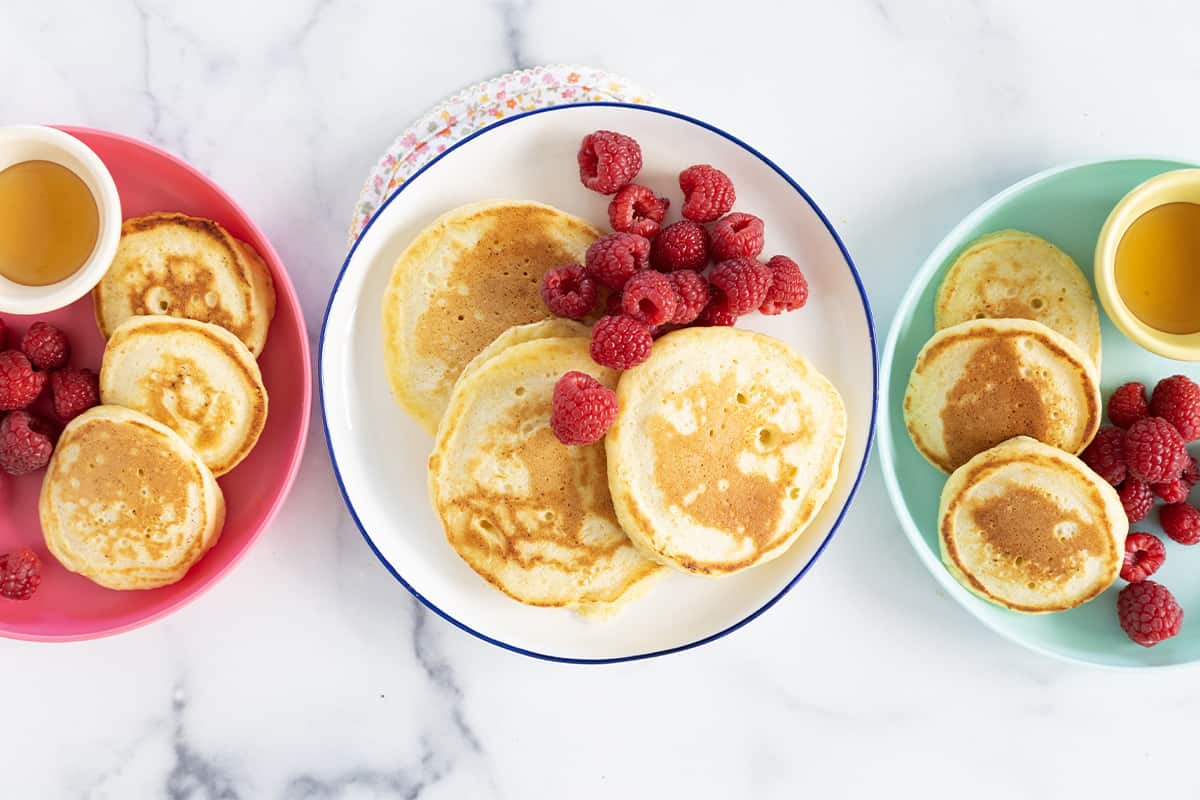 Ricotta pancakes on three plates with sides.