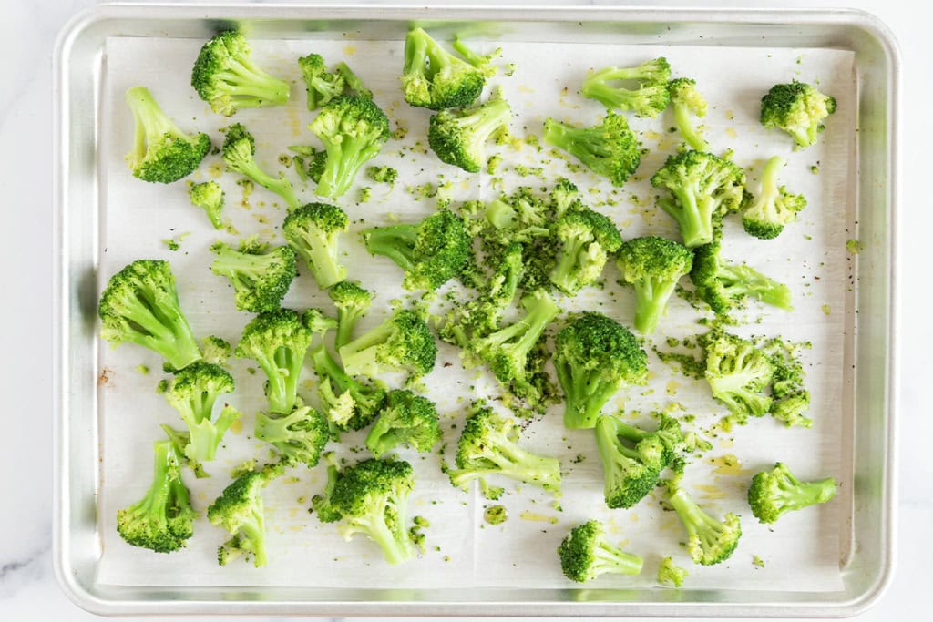 Frozen broccoli on baking sheet with seasonings.