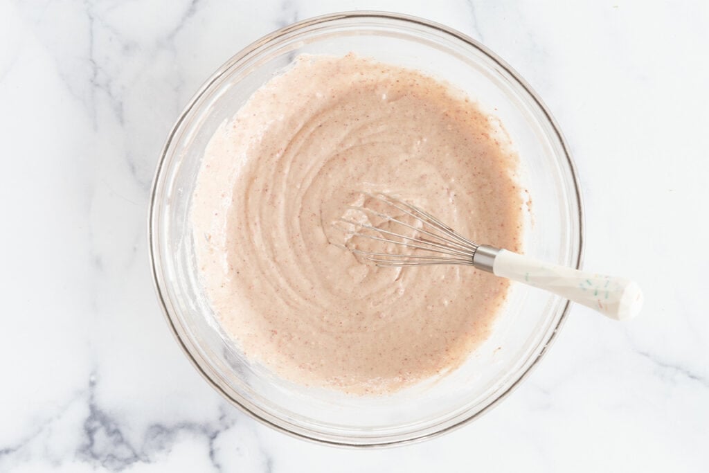 wet ingredients for strawberry pancakes with pink batter.