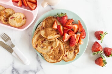 Strawberry pancake on two plates with strawberries.