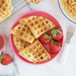 Yogurt waffles on pink plate with strawberries.
