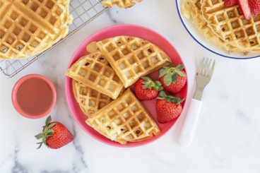 Yogurt waffles on pink plate with strawberries.