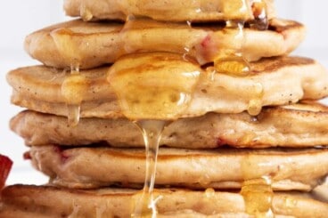 Stack of strawberry pancakes with syrup.