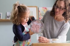 toddler pouring smoothie with mom