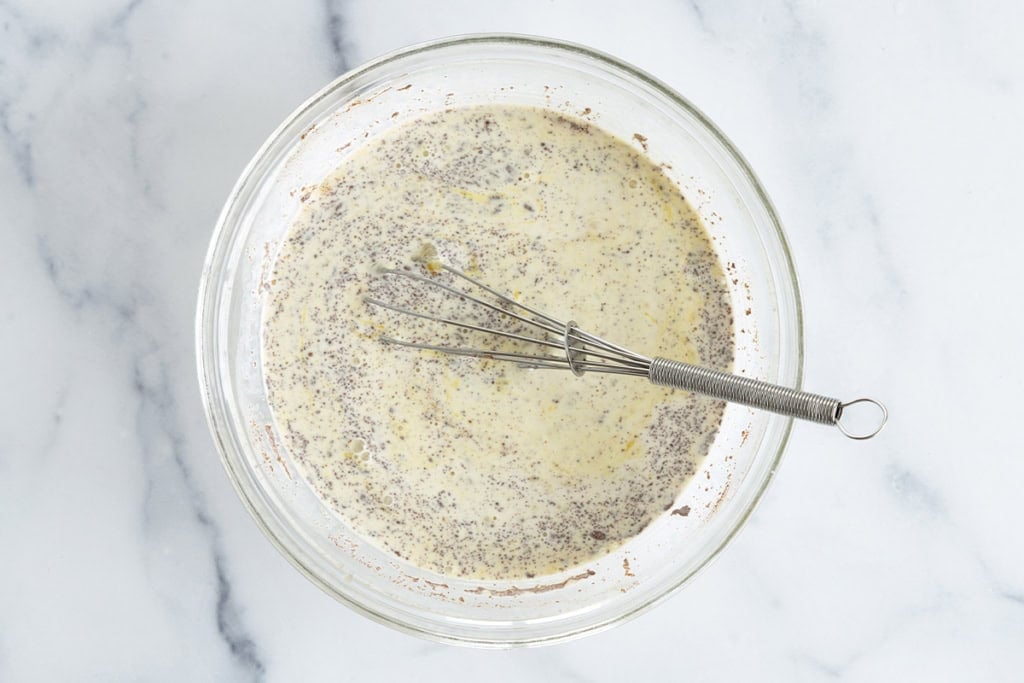 Batter for french toast casserole in glass bowl with whisk.