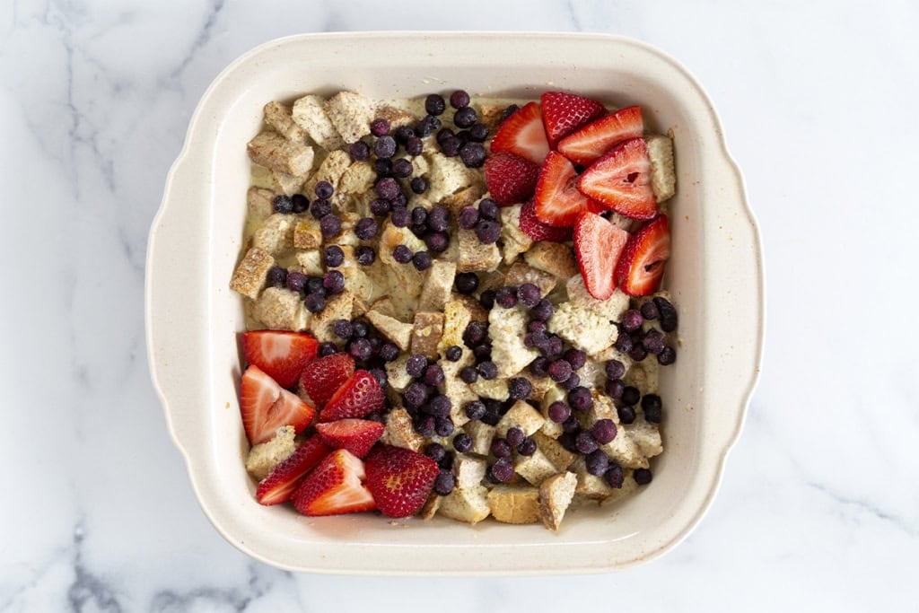 French Toast casserole with fruit in baking dish before baking.