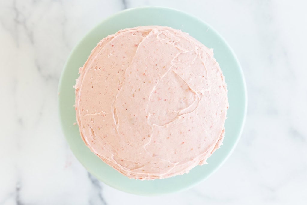 Vanilla cake with pink frosting on blue plate.