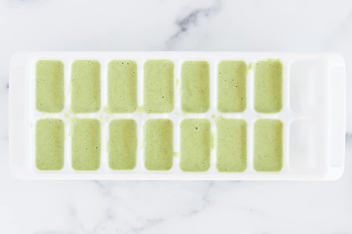 Green pasta sauce in ice cube tray.