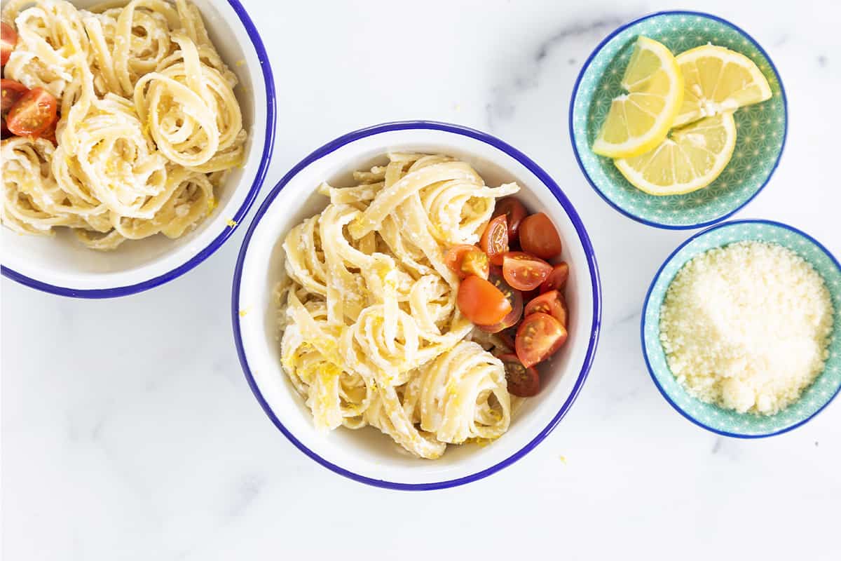 Lemon ricotta pasta in two bowls with cherry tomatoes. 