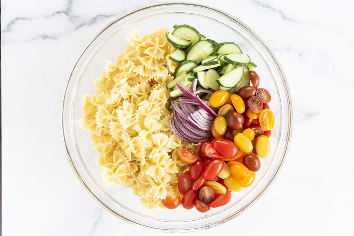 ingredients for pasta salad in glass bowl.